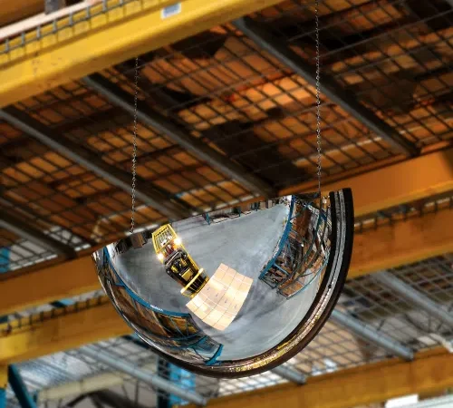 Convex safety mirror reflecting forklift in warehouse