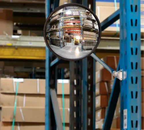 Convex safety mirror reflecting warehouse aisles
