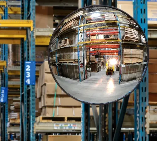 Convex safety mirror reflecting warehouse aisle and forklift