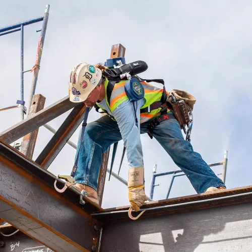 Construction worker securing steel beam at height