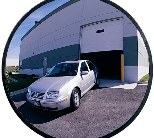 Silver car exiting warehouse reflected in convex mirror