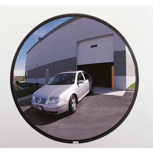 Convex mirror reflecting silver sedan leaving warehouse